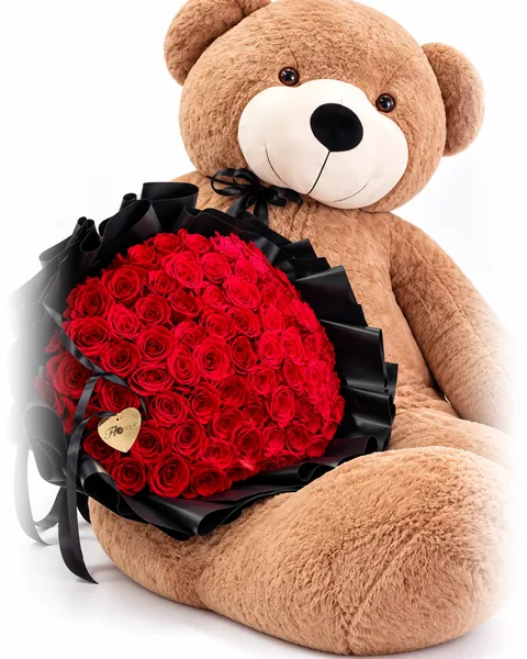 A large teddy bear holding a round bouquet of red roses in black wrapping